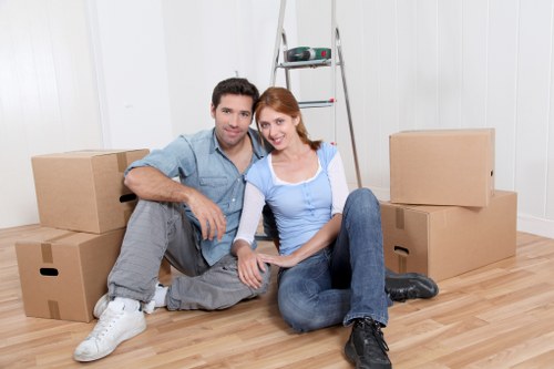 Movers carrying household items through a flat entrance in Islington